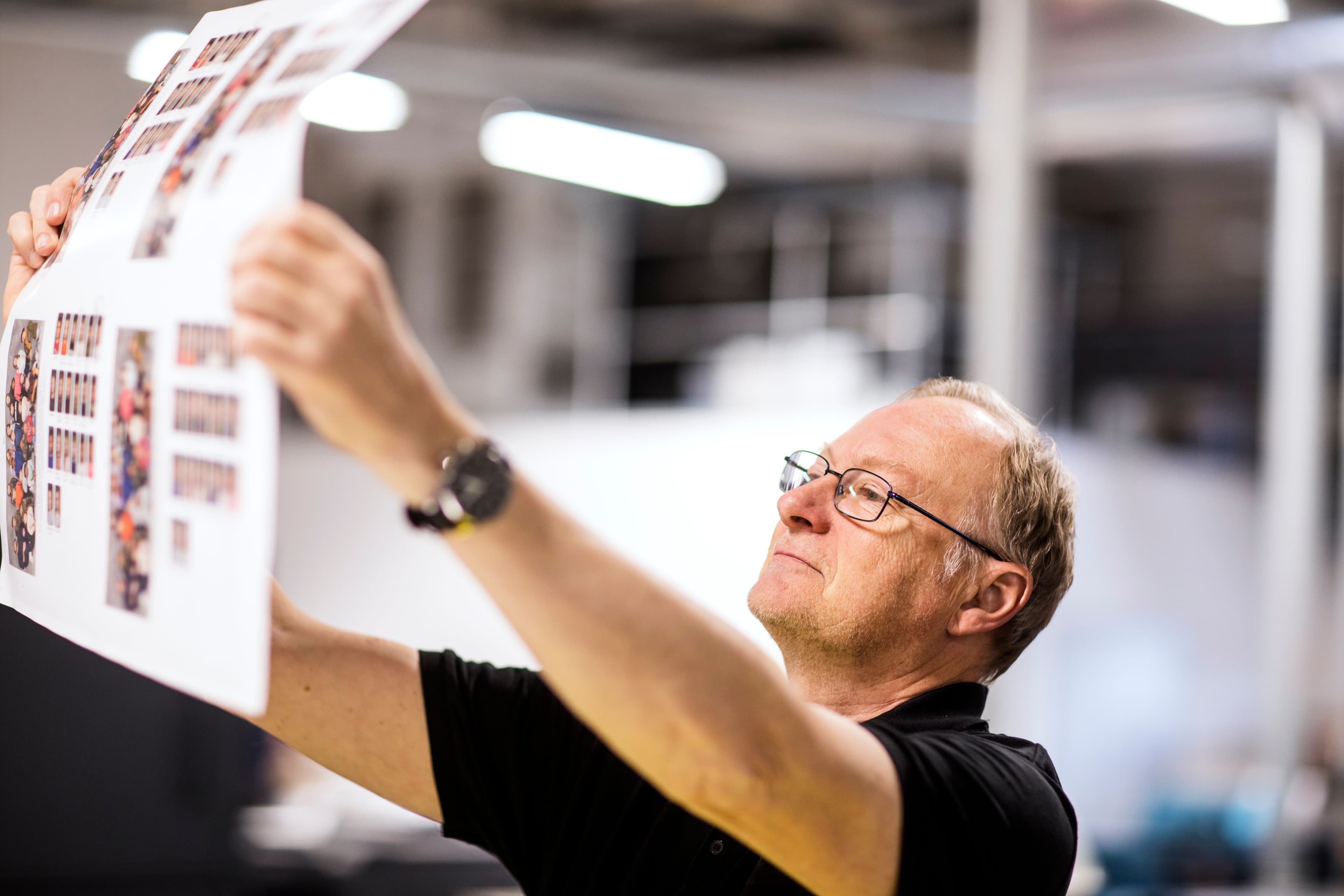 Print operator overlooking high quality printed sheet for premium books, brochures and magazines.